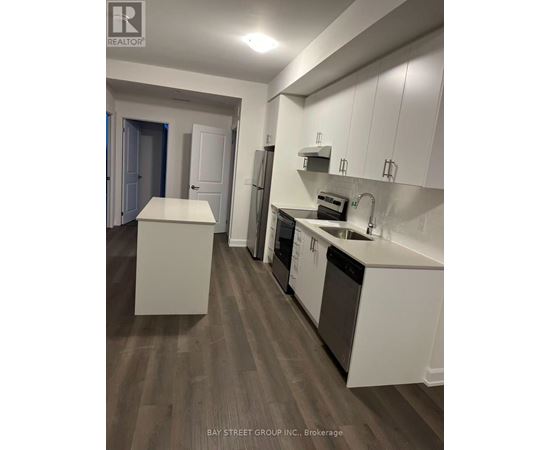 A kitchen with white cabinets and a wooden floor.