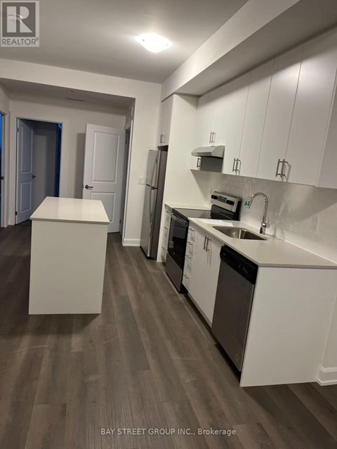 A kitchen with white cabinets and a wooden floor.