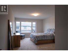 A bedroom with a bed, a chair, and a window overlooking a building.