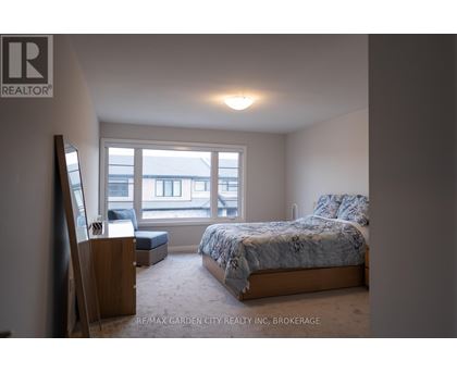 A bedroom with a bed, a chair, and a window overlooking a building.