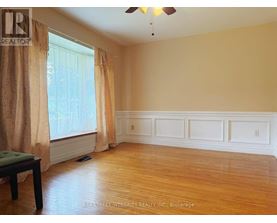 A room with a wooden floor and a window with curtains.