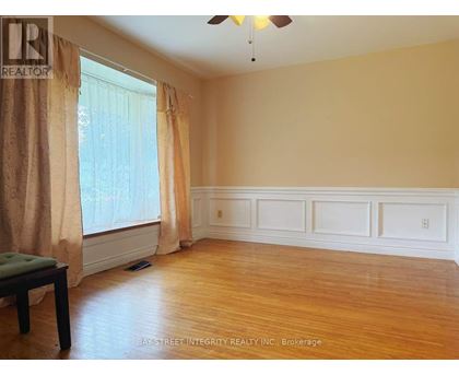 A room with a wooden floor and a window with curtains.