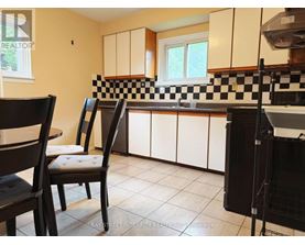 A kitchen with white cabinets and black and white checkered backsplash.