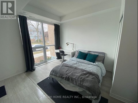 A bedroom with a large bed and a window with curtains.