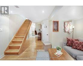 A living room with a couch, coffee table, and stairs.