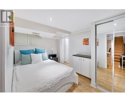 A bedroom with a white bed and a wooden floor.