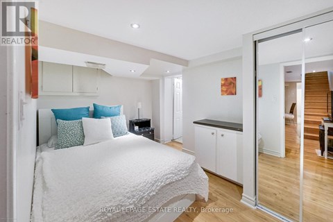 A bedroom with a white bed and a wooden floor.