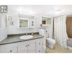 A bathroom with a sink, toilet, and mirror.