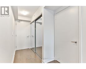 A white hallway with a glass door and a white door.