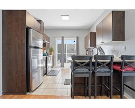 A kitchen with a table and chairs in front of a refrigerator.