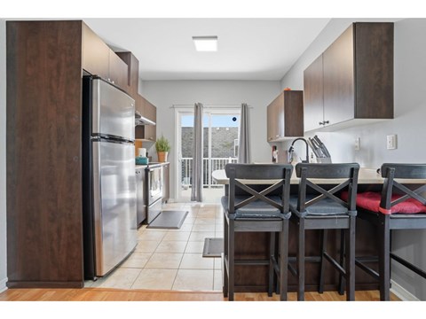 A kitchen with a table and chairs in front of a refrigerator.