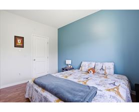A bedroom with a bed, pillows, and a lamp.