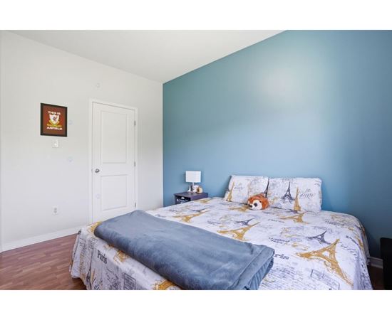 A bedroom with a bed, pillows, and a lamp.