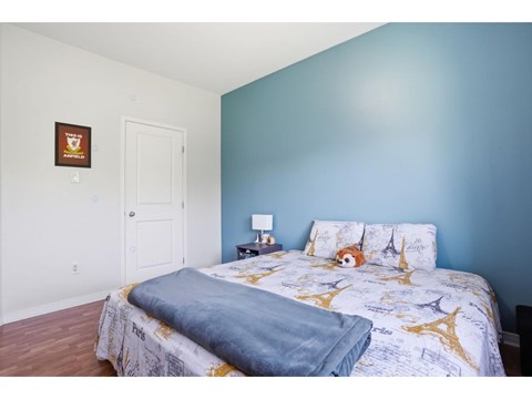 A bedroom with a bed, pillows, and a lamp.