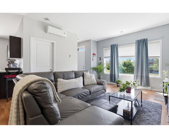 A modern living room with a grey sofa and a glass coffee table.