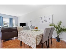 A dining room with a table set for two and a couch.