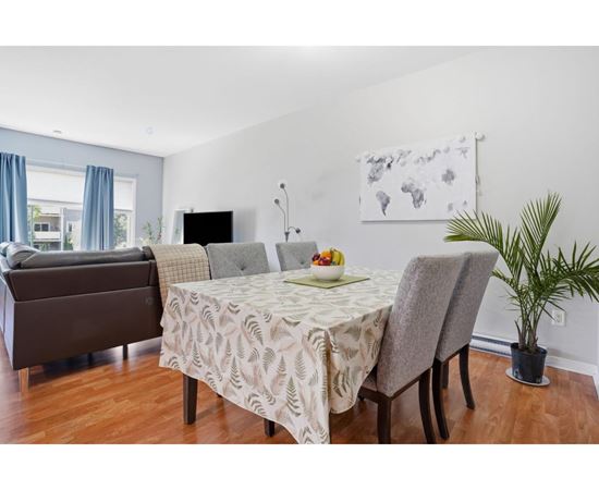 A dining room with a table set for two and a couch.