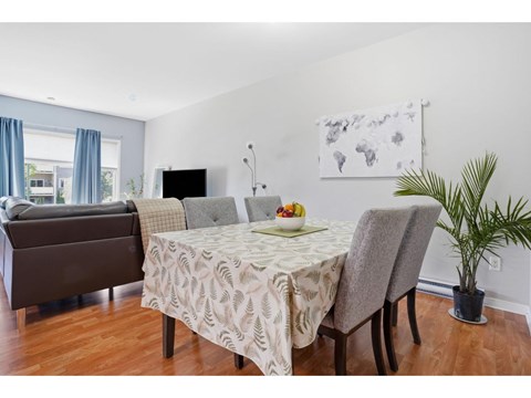 A dining room with a table set for two and a couch.