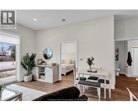 A well-lit, modern bedroom with a large bed and a small table with a plant on it.