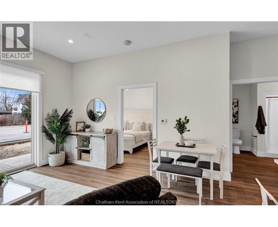 A well-lit, modern bedroom with a large bed and a small table with a plant on it.