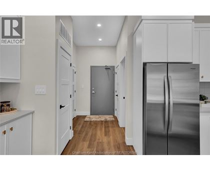 A kitchen with white cabinets and a stainless steel refrigerator.