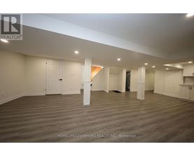 A spacious room with wooden flooring and white walls, ready for a new tenant.