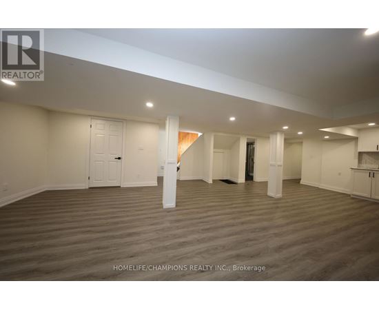 A spacious room with wooden flooring and white walls, ready for a new tenant.