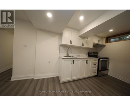 A kitchen with white cabinets and a wooden floor.