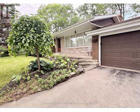 A house with a brown garage door and a tree in front of it.