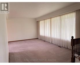 A room with a carpeted floor and a window with curtains.