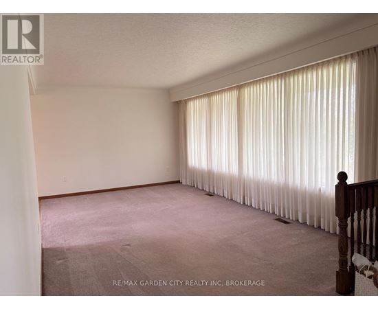 A room with a carpeted floor and a window with curtains.