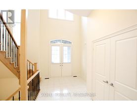 A spacious room with a staircase on the left and a doorway leading to another room on the right.