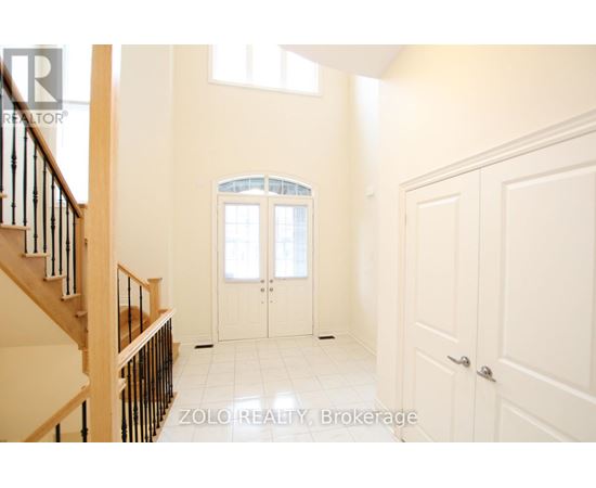 A spacious room with a staircase on the left and a doorway leading to another room on the right.