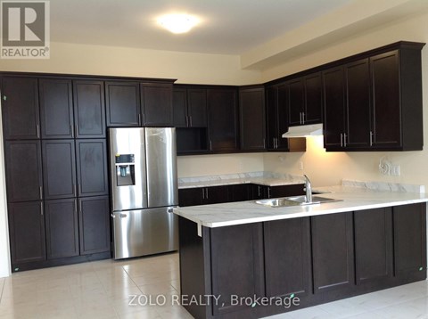 A kitchen with black cabinets and a stainless steel refrigerator.