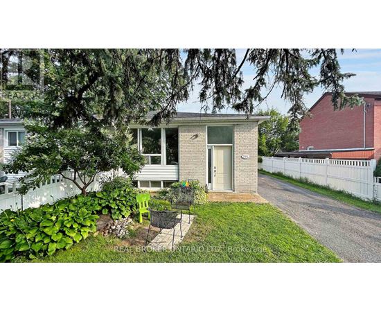 A small house with a green chair and a tree in front.