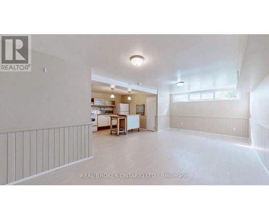 A spacious empty room with a kitchen area in the background.