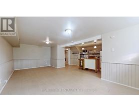 A spacious room with a kitchenette in the background.