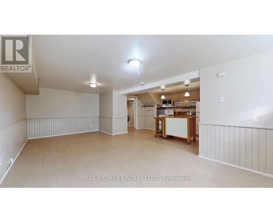 A spacious room with a kitchenette in the background.