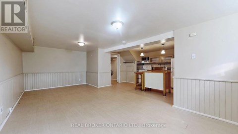 A spacious room with a kitchenette in the background.