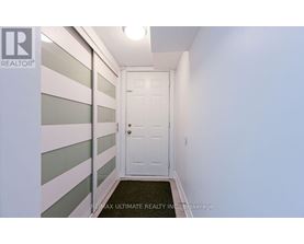 A hallway with a white door and a black doormat.