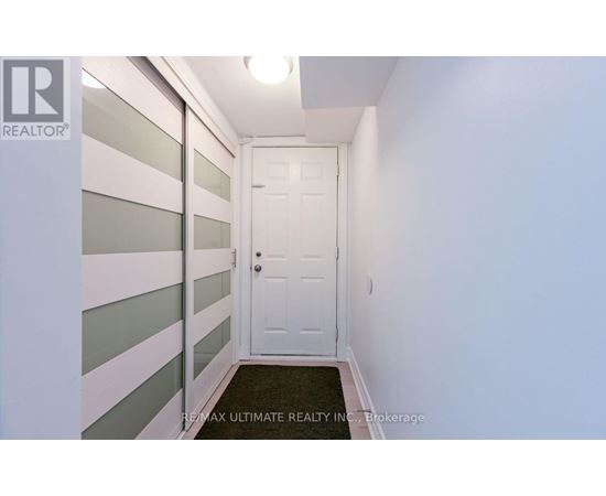 A hallway with a white door and a black doormat.
