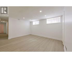 A spacious room with wooden flooring and white walls.