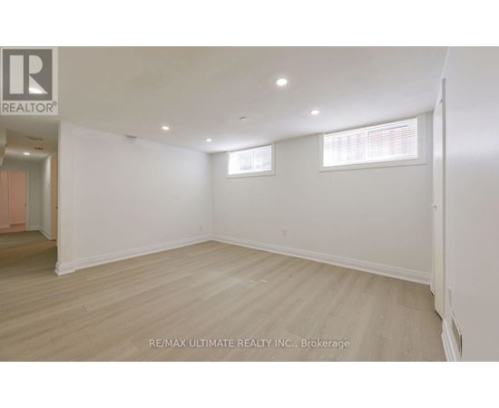 A spacious room with wooden flooring and white walls.