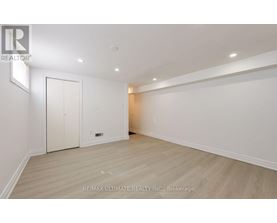 A spacious room with a white door and a wooden floor.