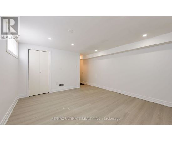 A spacious room with a white door and a wooden floor.