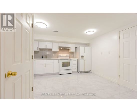 A white kitchen with a refrigerator, oven, and cabinets.
