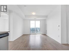 A spacious room with wooden flooring and a large window overlooking a balcony.