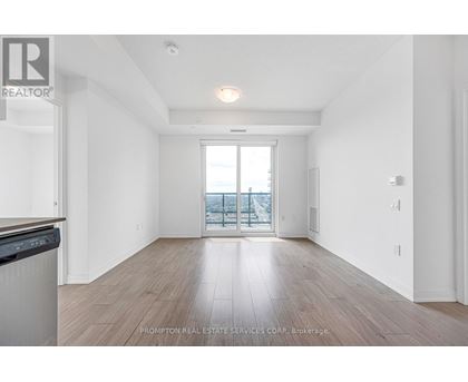 A spacious room with wooden flooring and a large window overlooking a balcony.