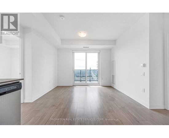 A spacious room with wooden flooring and a large window overlooking a balcony.