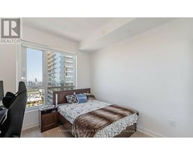 A bedroom with a large bed and a view of a cityscape through the window.